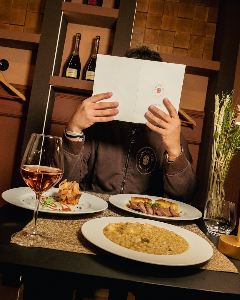 Tavolo apparecchiato con piatti e calice di rosato